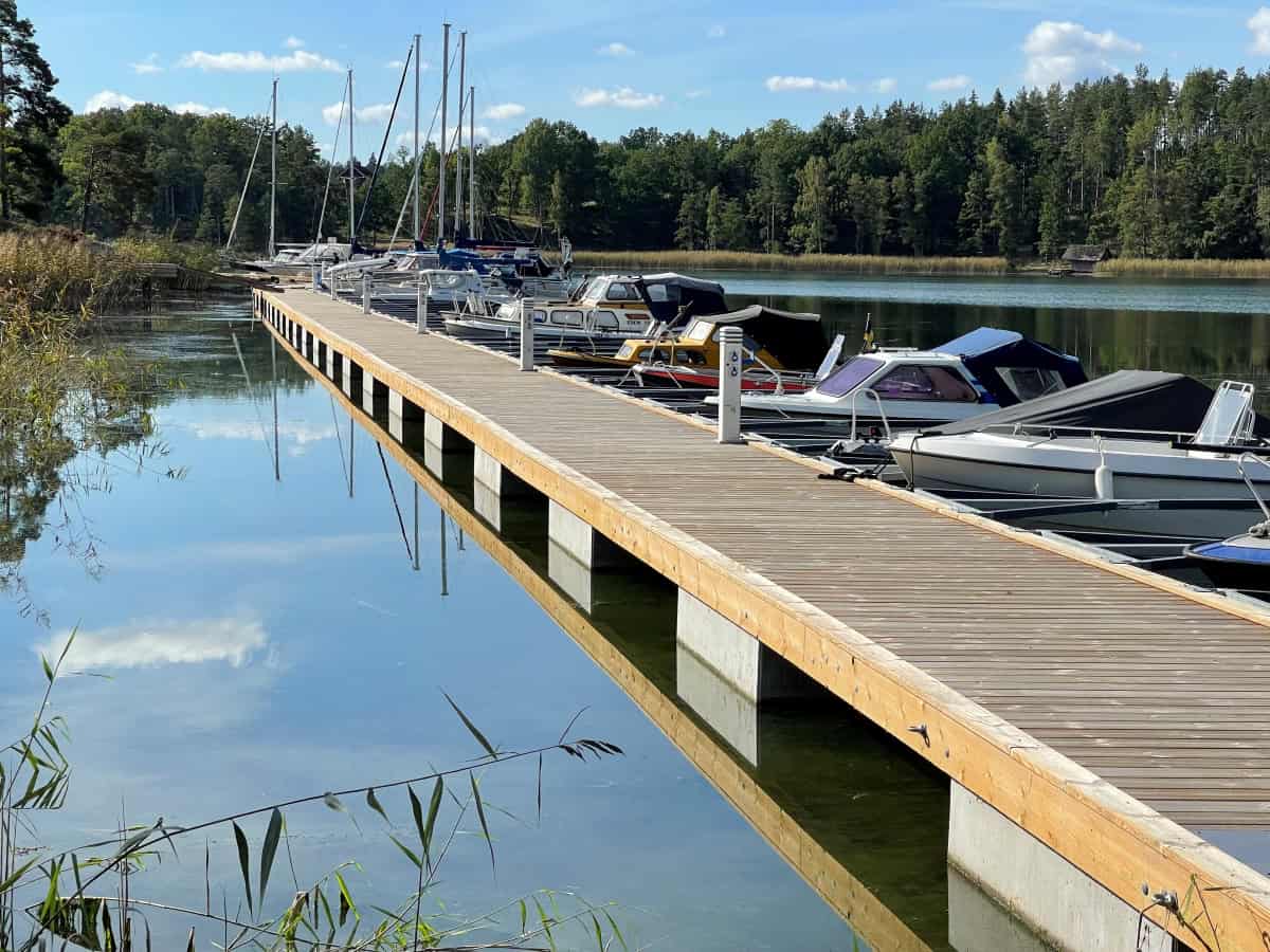 Trä- och betongbrygga med Y-bommar och förtöjda båtar