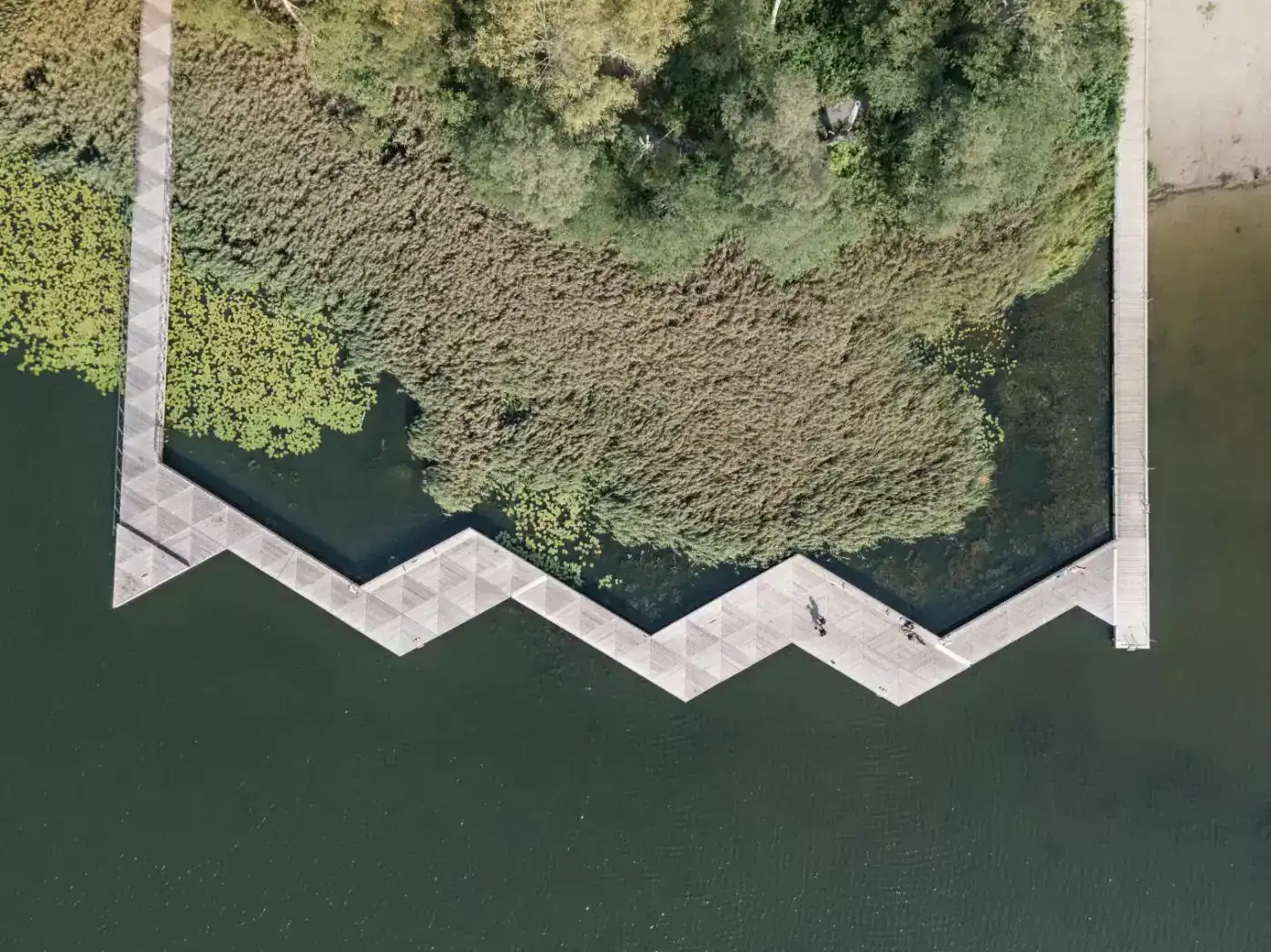 Unik gångbro av betongpontoner med trallvirke i trekantmönster i Farsta strand taget uppifrån